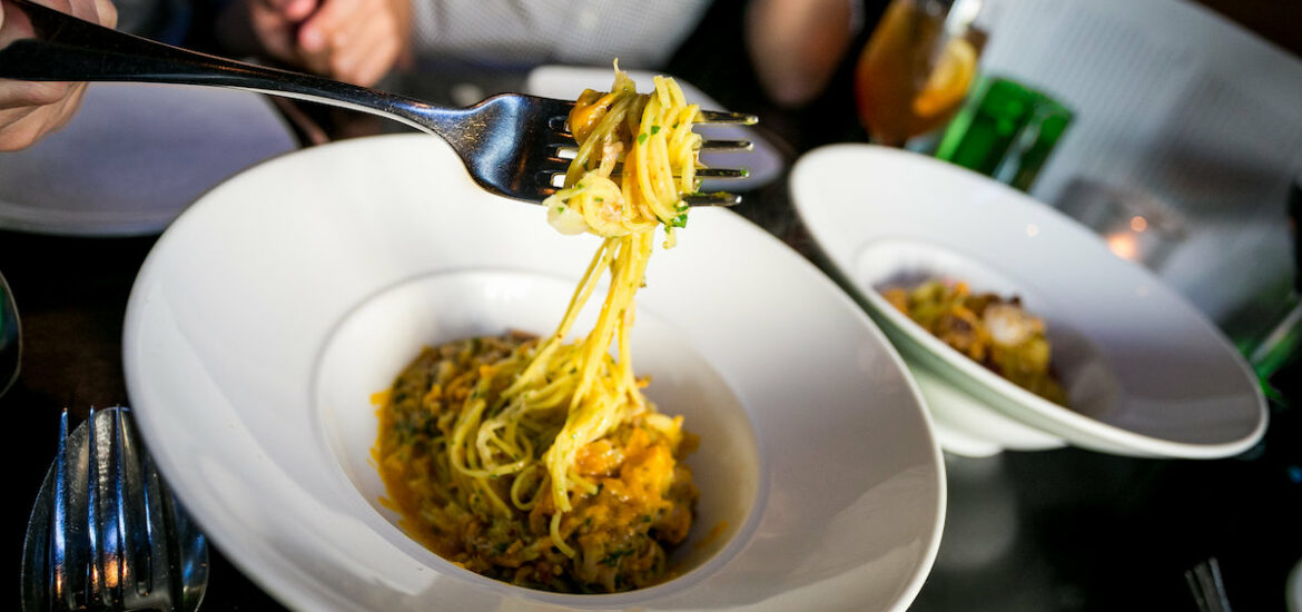 Someone pulls up long pasta with a fork at SPQR, one of the best Italian restaurants in San Francisco