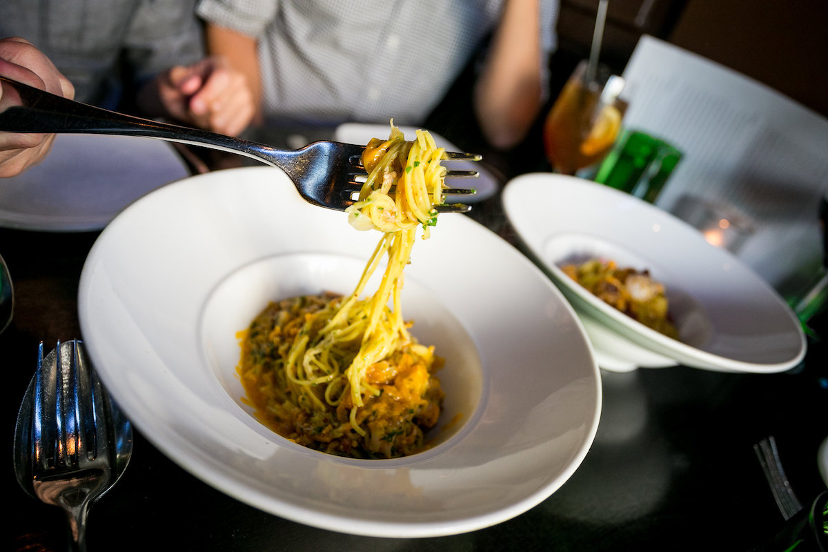 Someone pulls up long pasta with a fork at SPQR, one of the best Italian restaurants in San Francisco