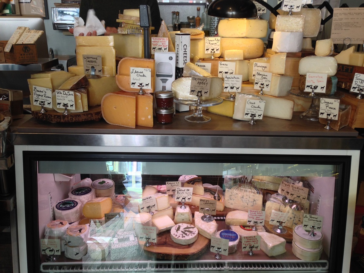 cheese counter filled with wheels and wedges of cheese in a San Francisco cheese shop