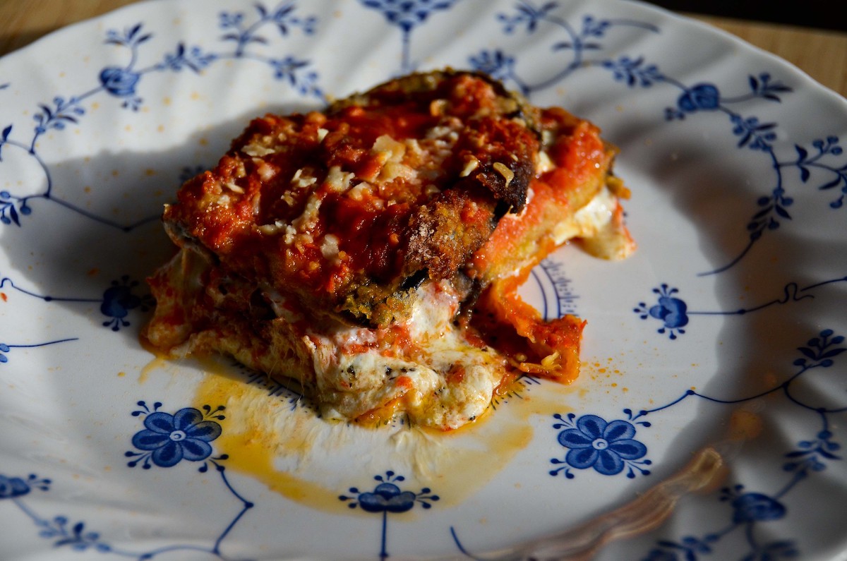 close up of a blue and white plate with vegetarian eggplant parmesan