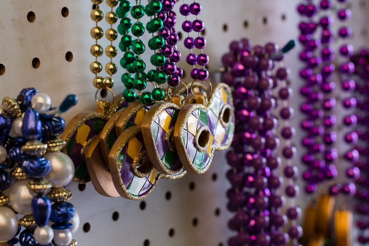 Strands of beads and mardi gras mask necklaces hang in a store