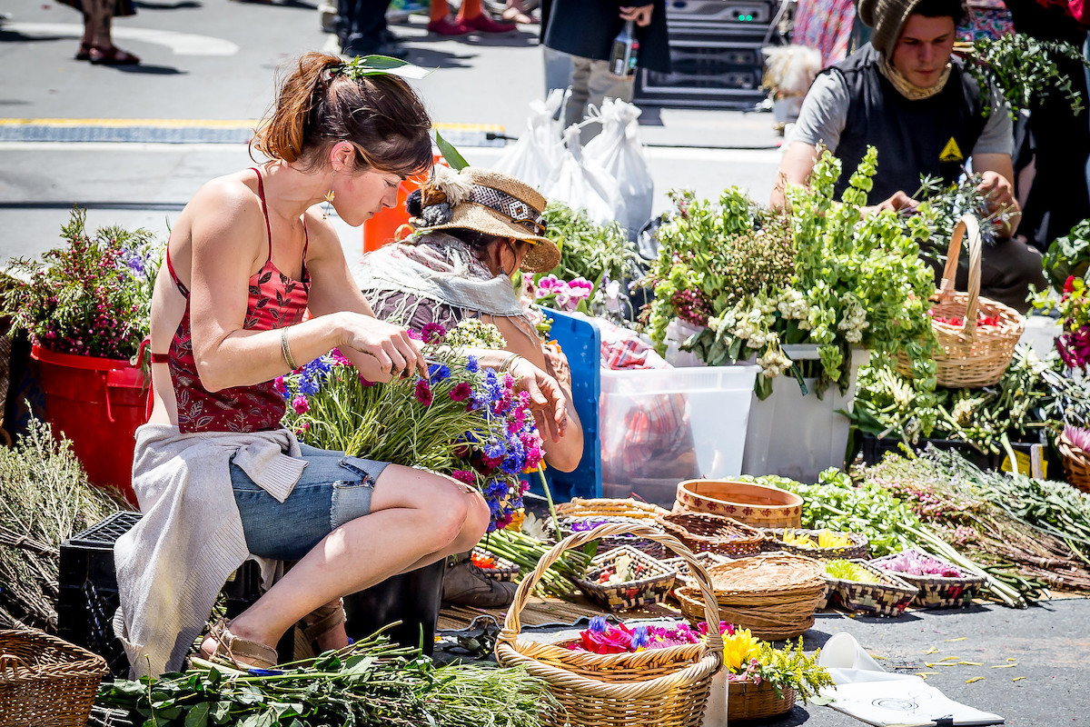 a woman organizes fresh flowers at a street market