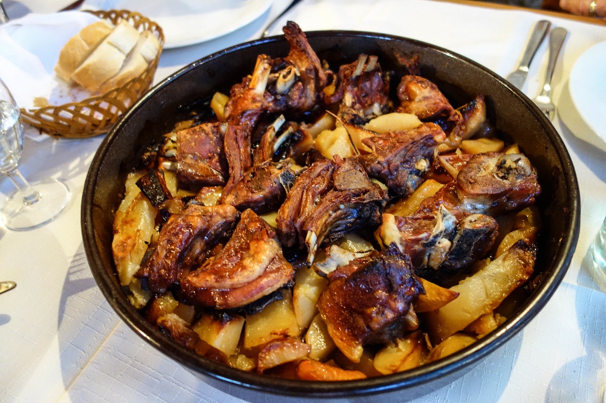 Croatian lamb peka served in a round dish with bread, potatoes, and vegetables at an eastern european restaurants chicago