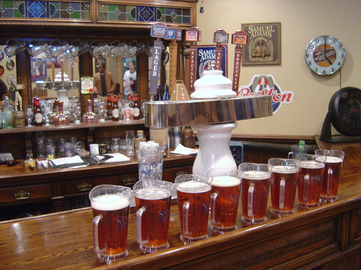 Several pitchers of beer lined up on a bar