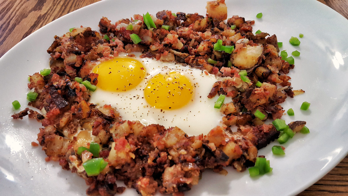 close up of a plate of corned beef hash with two sunny side up eggs