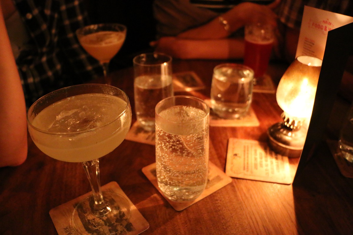 Several different colored cocktails displayed on a table at a dark cocktail restaurant
