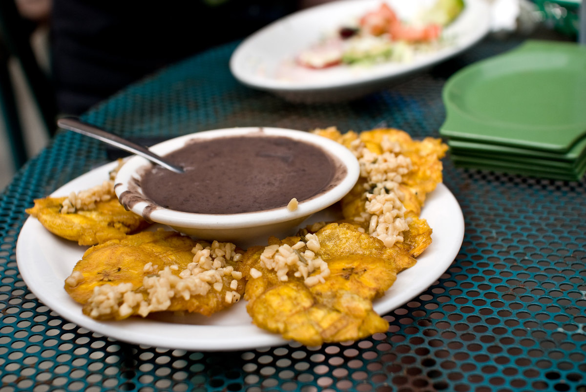 close up of a dish of fried garlin plantains with a black bean sauce at Irazu, a Latin American restaurant in Chicago