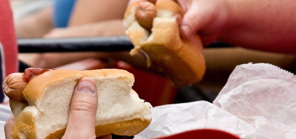 extreme close up of two people each holding one "Fenway Frank," a hot dog in a bread bun