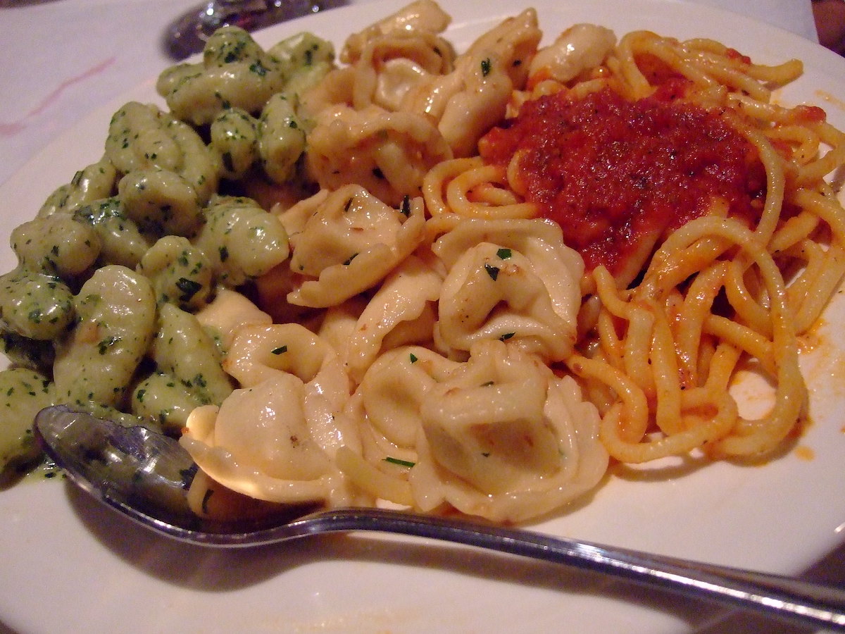 Close up of a plate of pasta from Lucia Ristorante, a North End Boston restaurant, with three kinds of pasta next to each other on one plate, giving the impression of the green, white, and red Italian flag