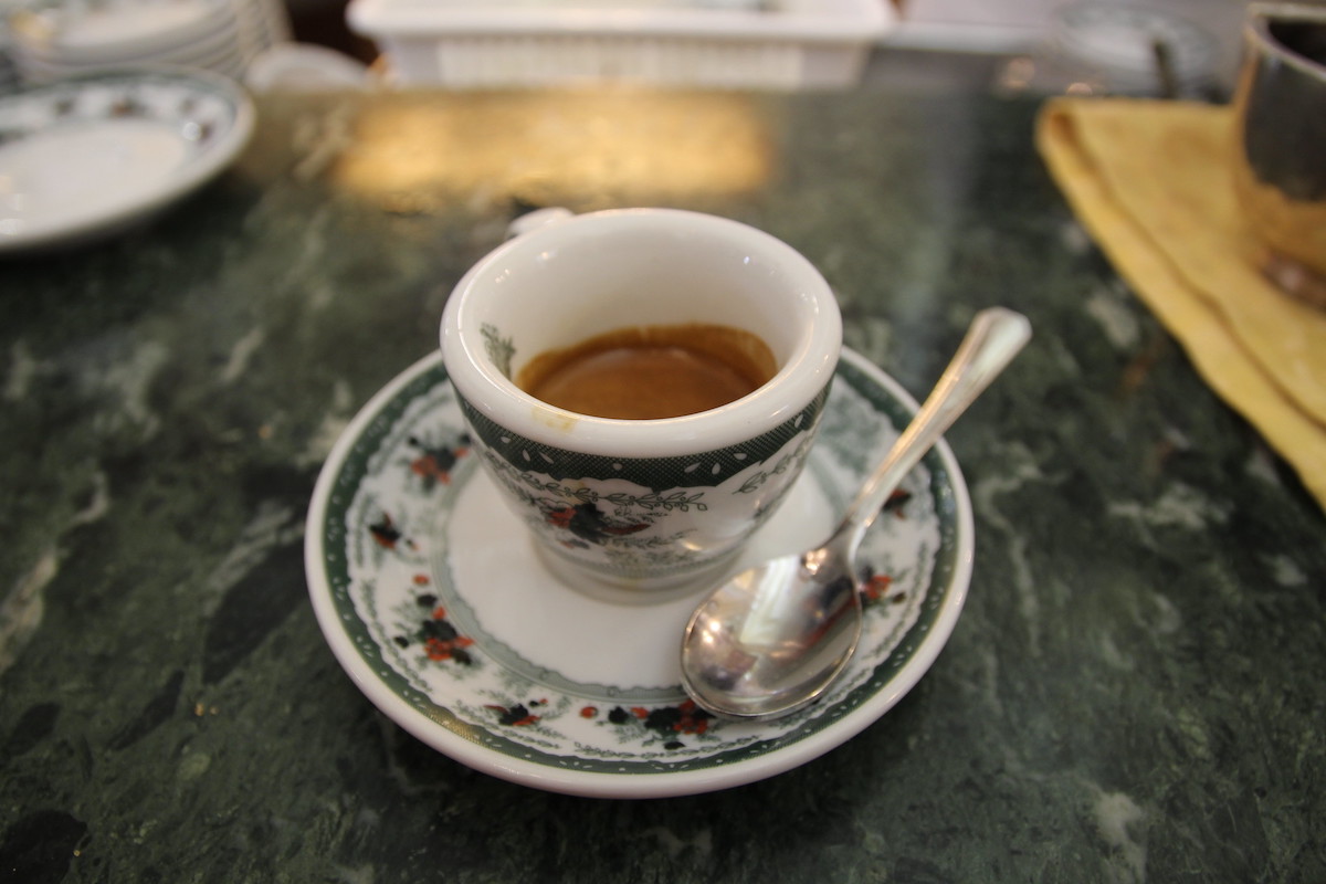Close up of a highly decorated espresso cup and saucer on a green marble coffee bar counter at Gran Caffé Gambrinus in Naples, a classic coffee house
