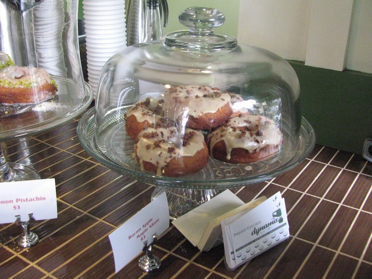 A glass pastry case with bacon maple glaze donuts inside