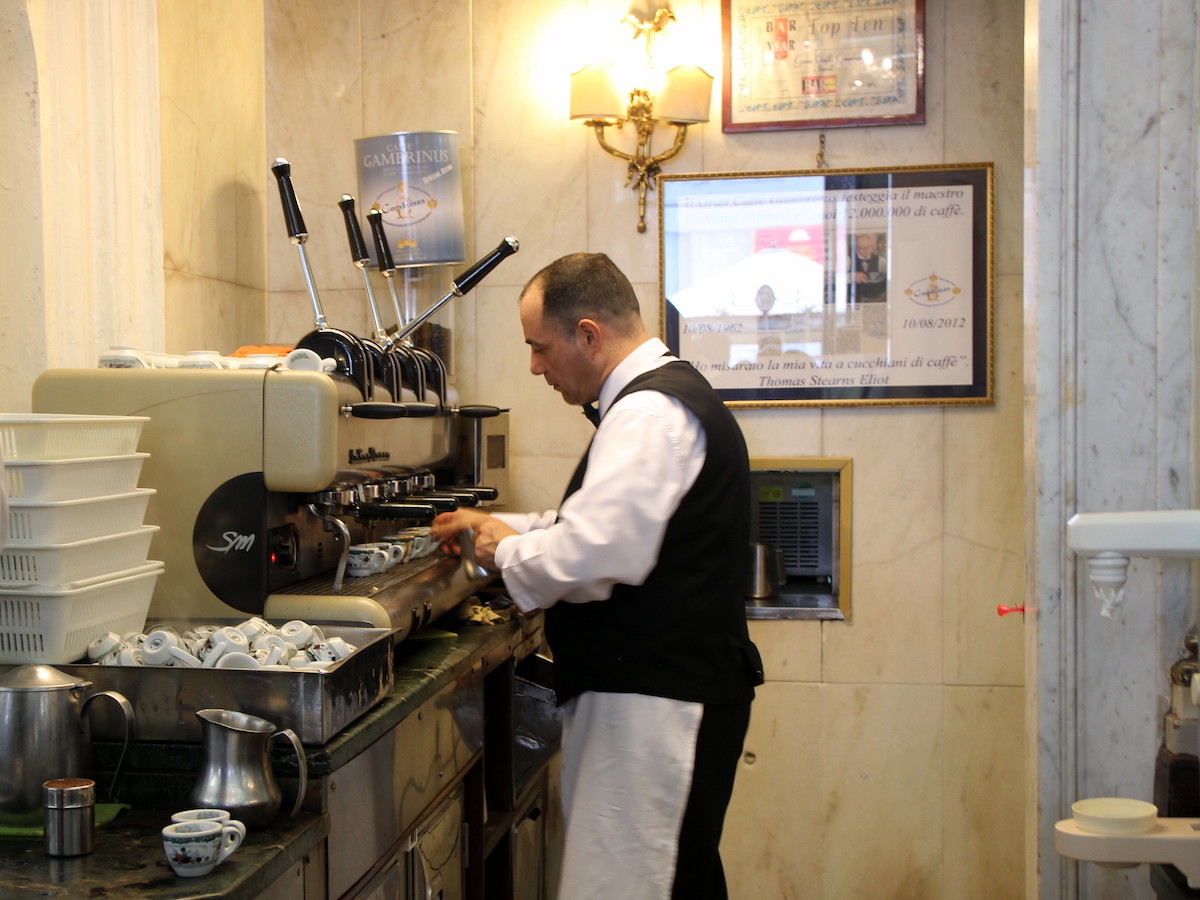 A barista in Gran Caffe Cambrinus in Naples prepares an espresso using a big espresso machine.