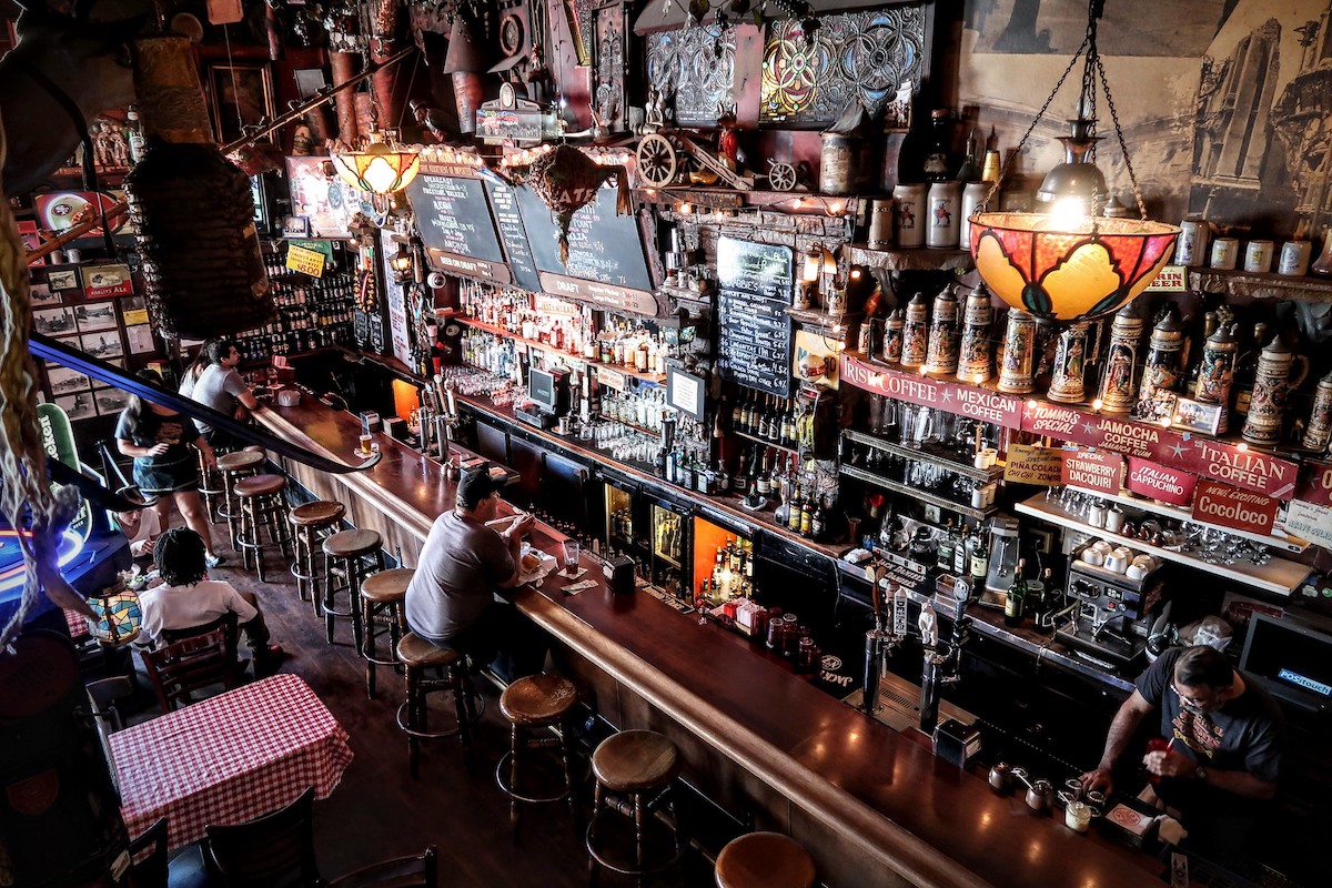 People sit at the bar in Tommy's Joynt, a famous San Francisco restaurant and bar. The bar is is loaded with bottles, and the interior is full of dark, polished wood