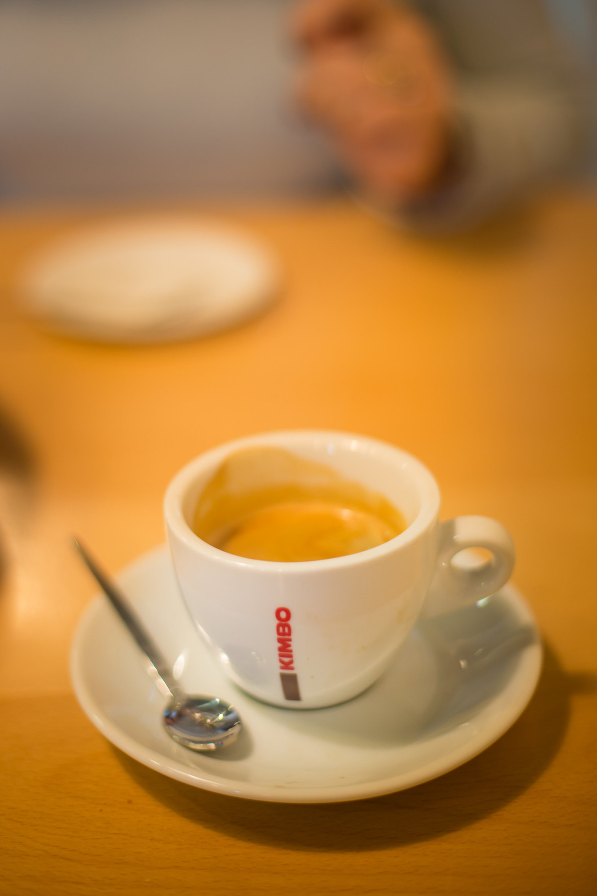 close up of a small white espresso cup with read letters on the side reading "Kimbo," a common coffee roaster found in Naples