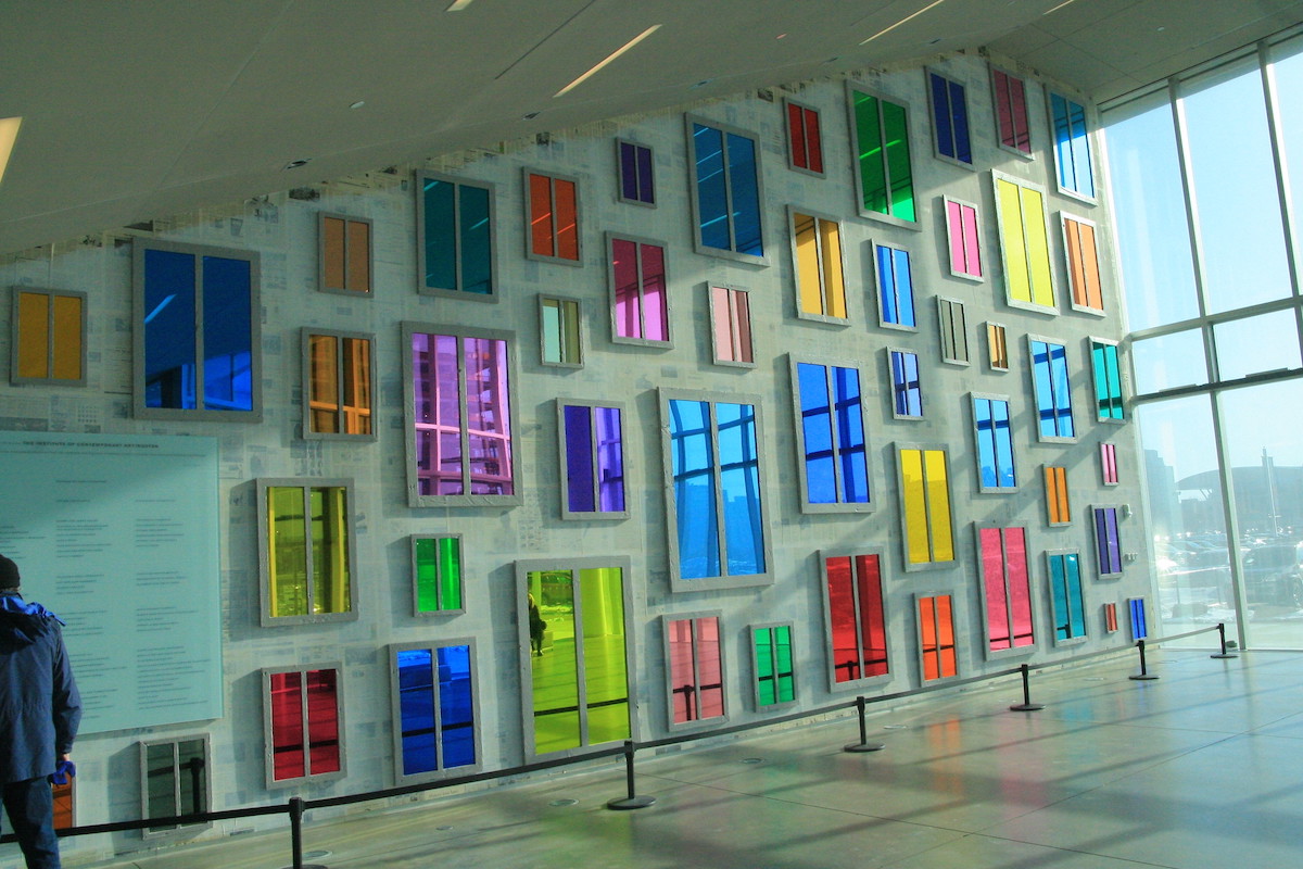 contemporary art installation of colorful reflective windows covering a wall