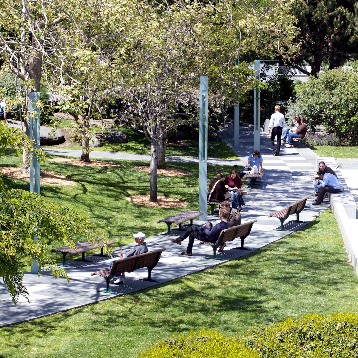 A walking path lined with people sitting on benches in the Yerba Buena Gardens in San Francisco