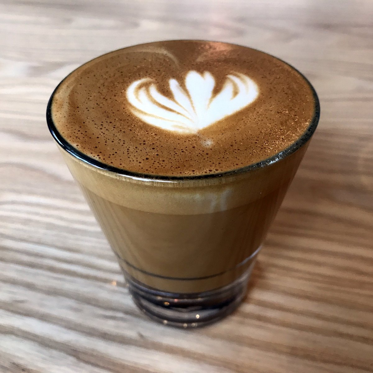 close up of latte art on a very small coffee drink in a clear glass