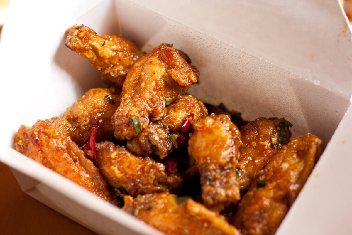 Close up of a white to go box filled with crispy chicken wings