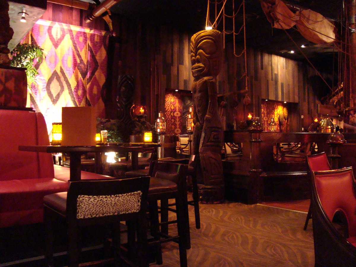 Interior shot of the Tonga Room & Hurricane Bar in San Francisco. It is dimly lit with lanters and tiki statues around