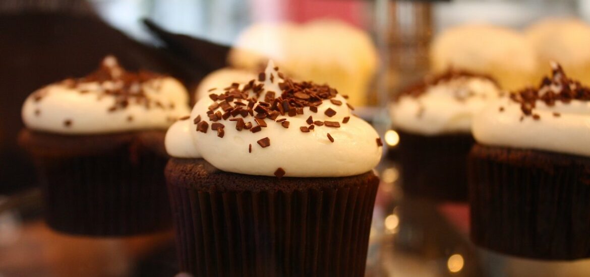 Close up of a platter of chocolate cupcakes with white frosting and dusted with chocolate sprinkles.