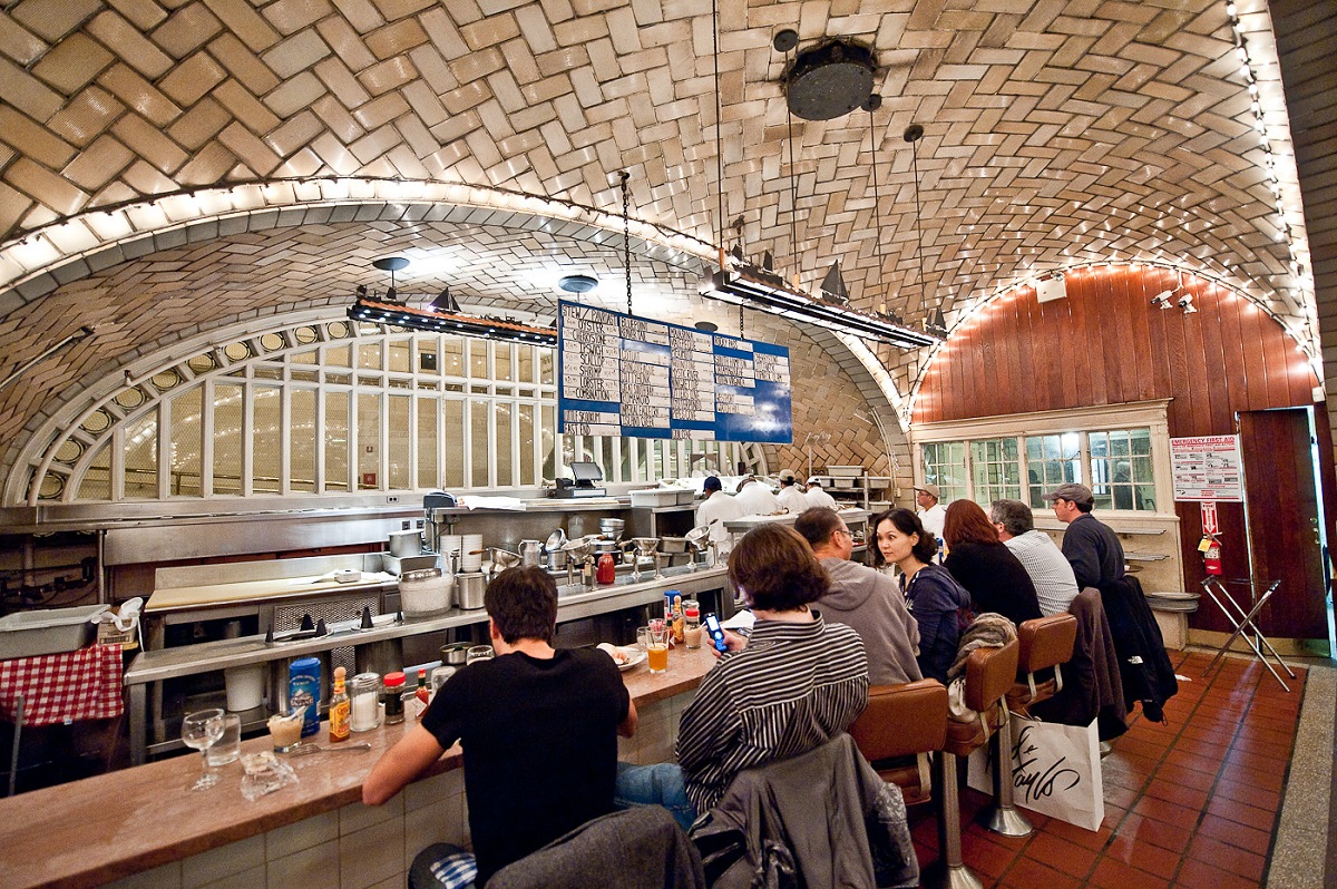 A well-lit eating area with customers having fish of a train station