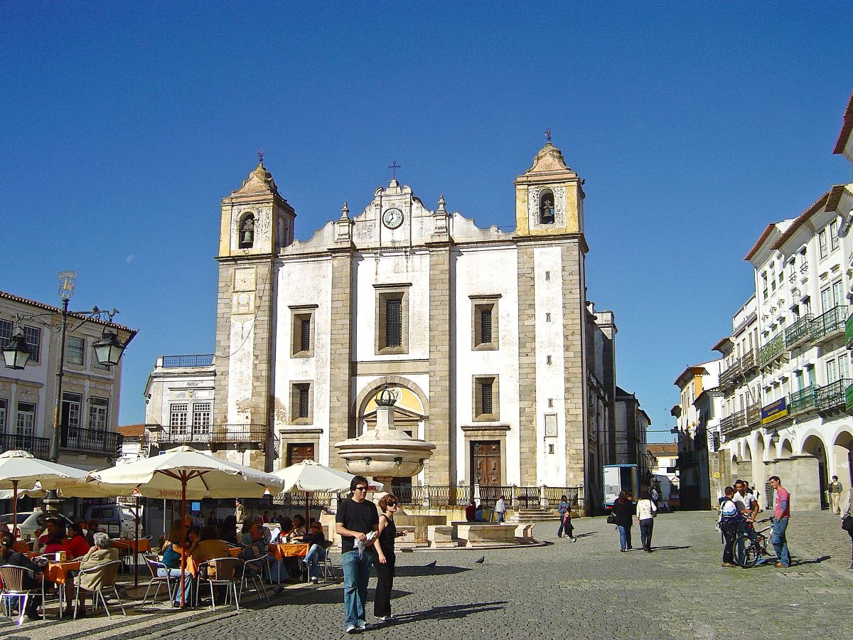 people walking through a plaza near restaurants in Evora, Portugal