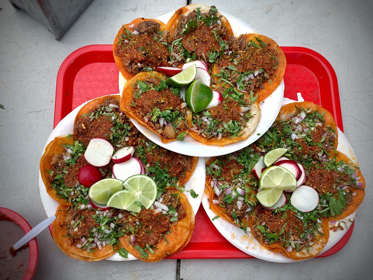 Three plates with 5 small tacos, radishes, and limes on a red tray