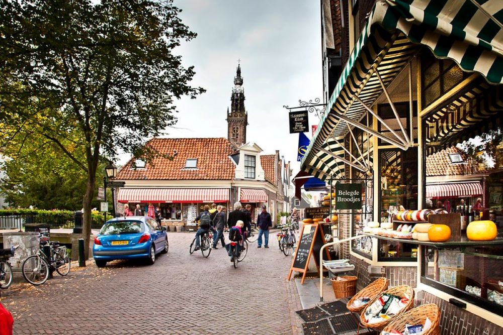 A street in Edam, Netherlands displaying a shop selling cheese, and people riding their bikes