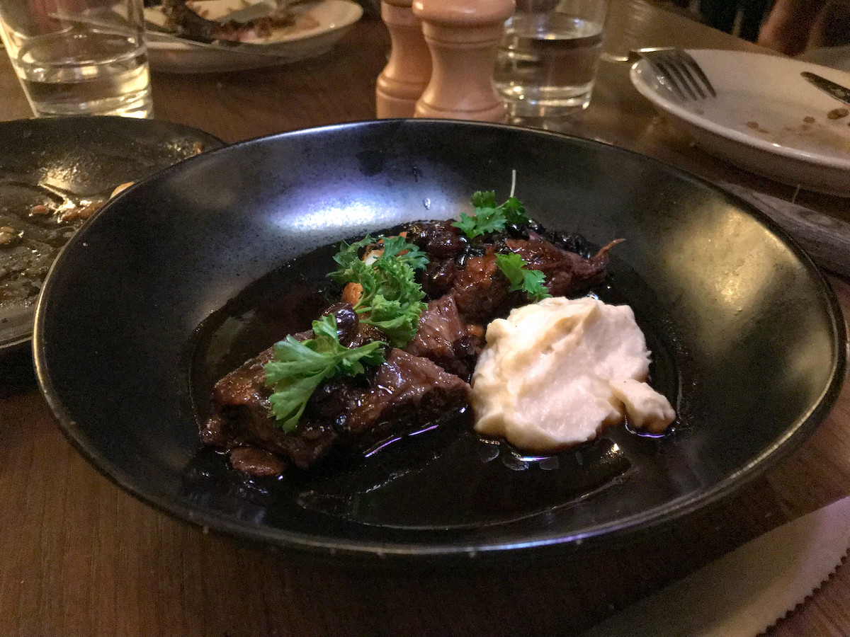 beef short rib with mashed potatoes on a black plate