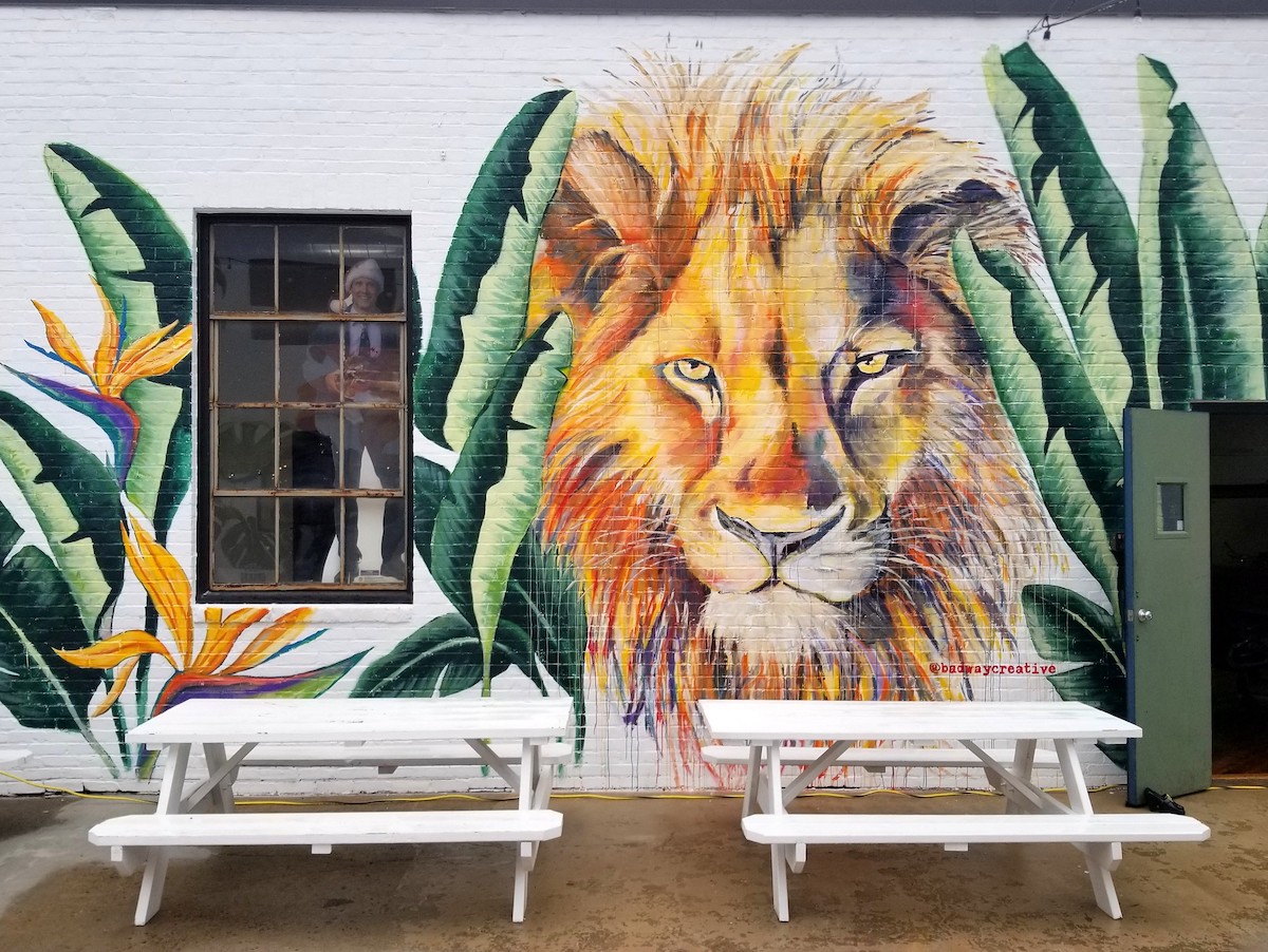 A large mural of a male lion among birds of paradise