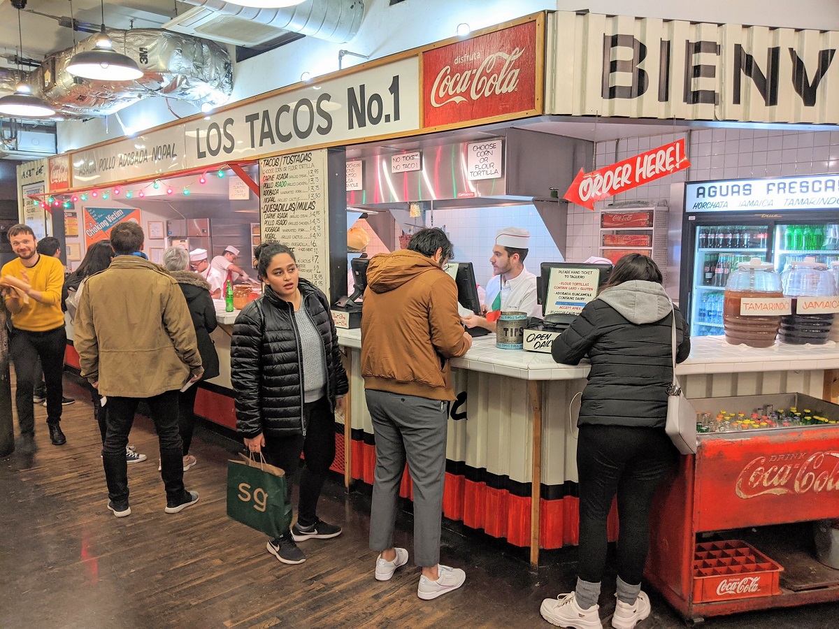 Customers wait in line at an indoor taco stand in New York during the winter