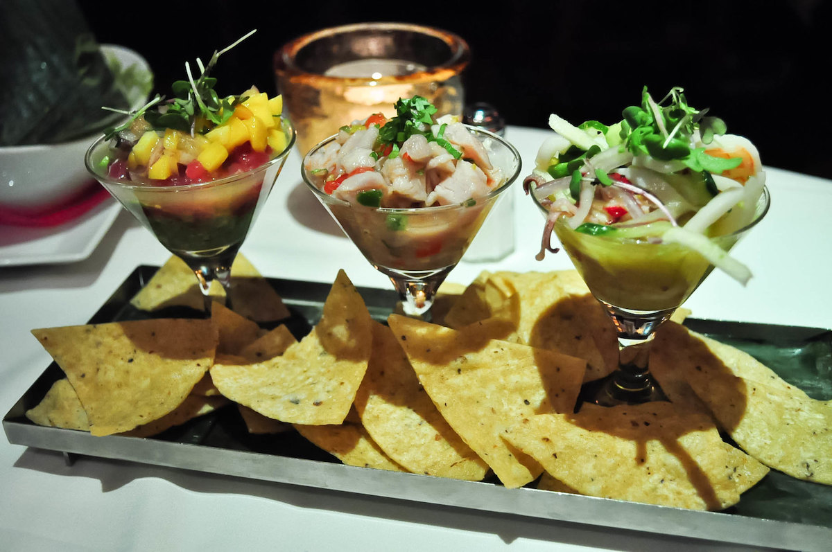 close up of 3 martini style glasses holding ceviche, with some tortilla chips on a plate at Topolobampo, one of the best restaurants for Mexican food in Chicago