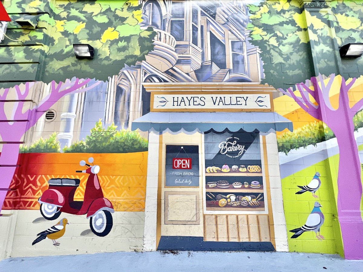 A colorful mural in San Francisco's Hayes Valley of a bakery with a city scape behind
