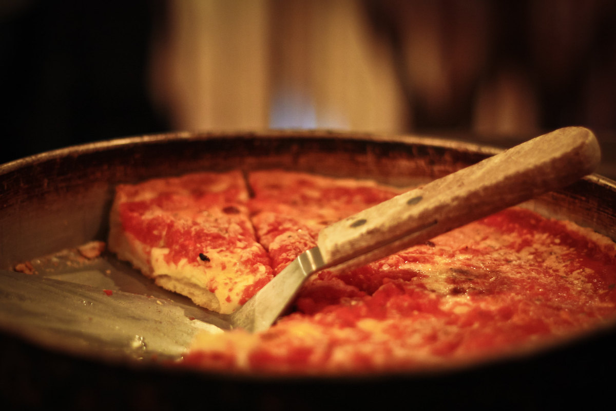 Close up of a pan of deep dish pizza and serving spatula