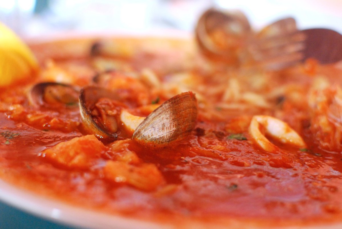 Extreme close up of a bowl of cioppino, a tomato-based seafood stew with clams