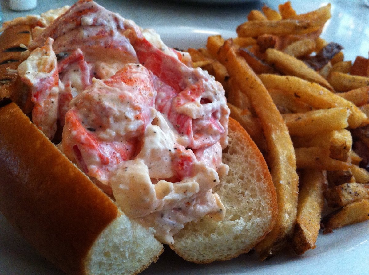 extreme close up of a plate with a cold lobster roll and fries