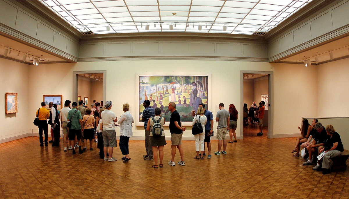 Museum visitors looking at large paintings in an art gallery at the Art Institute of Chicago