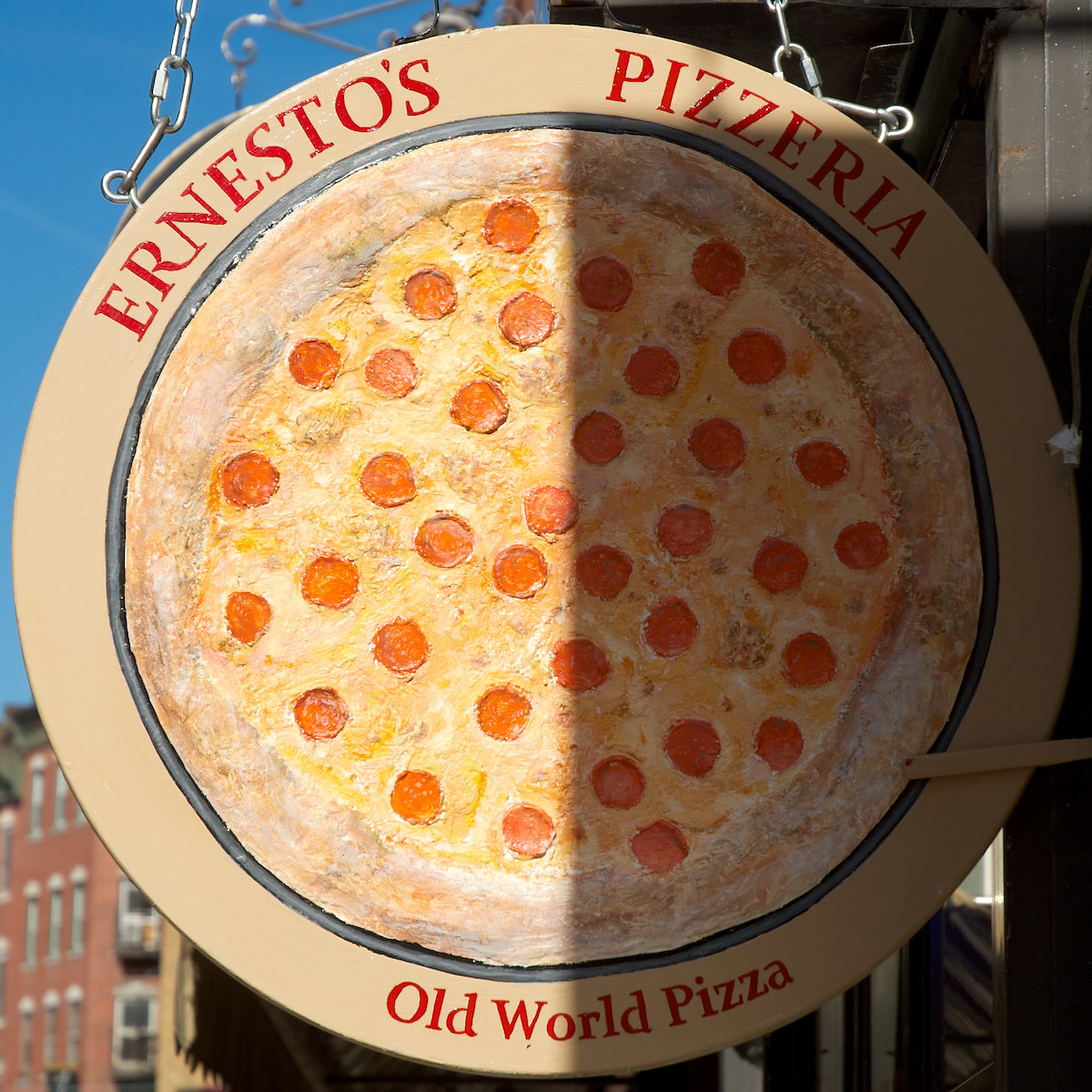 A round sign with a large picture of a pepperoni pizza and the name "Ernesto's Pizzeria" in red letters. Ernesto's is a popular North End Boston restaurant.