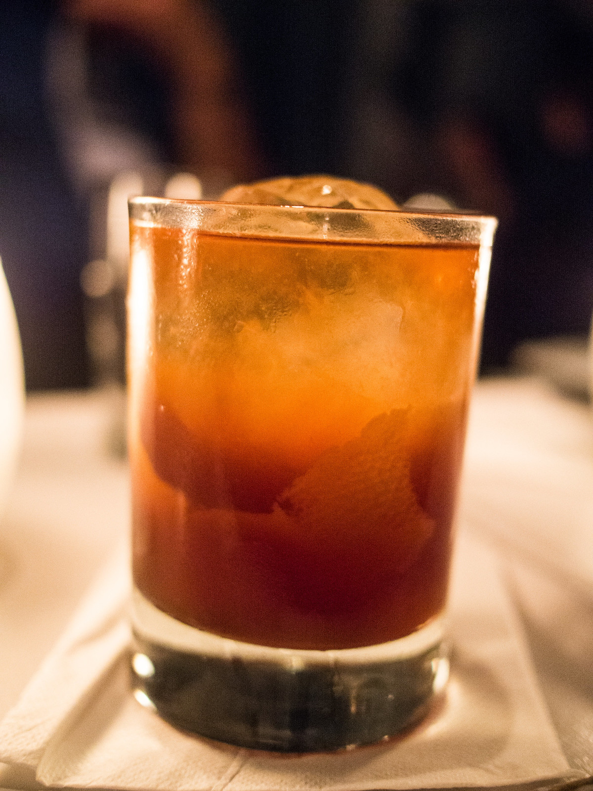 Close up of a dark orange cocktail in a rocks glass