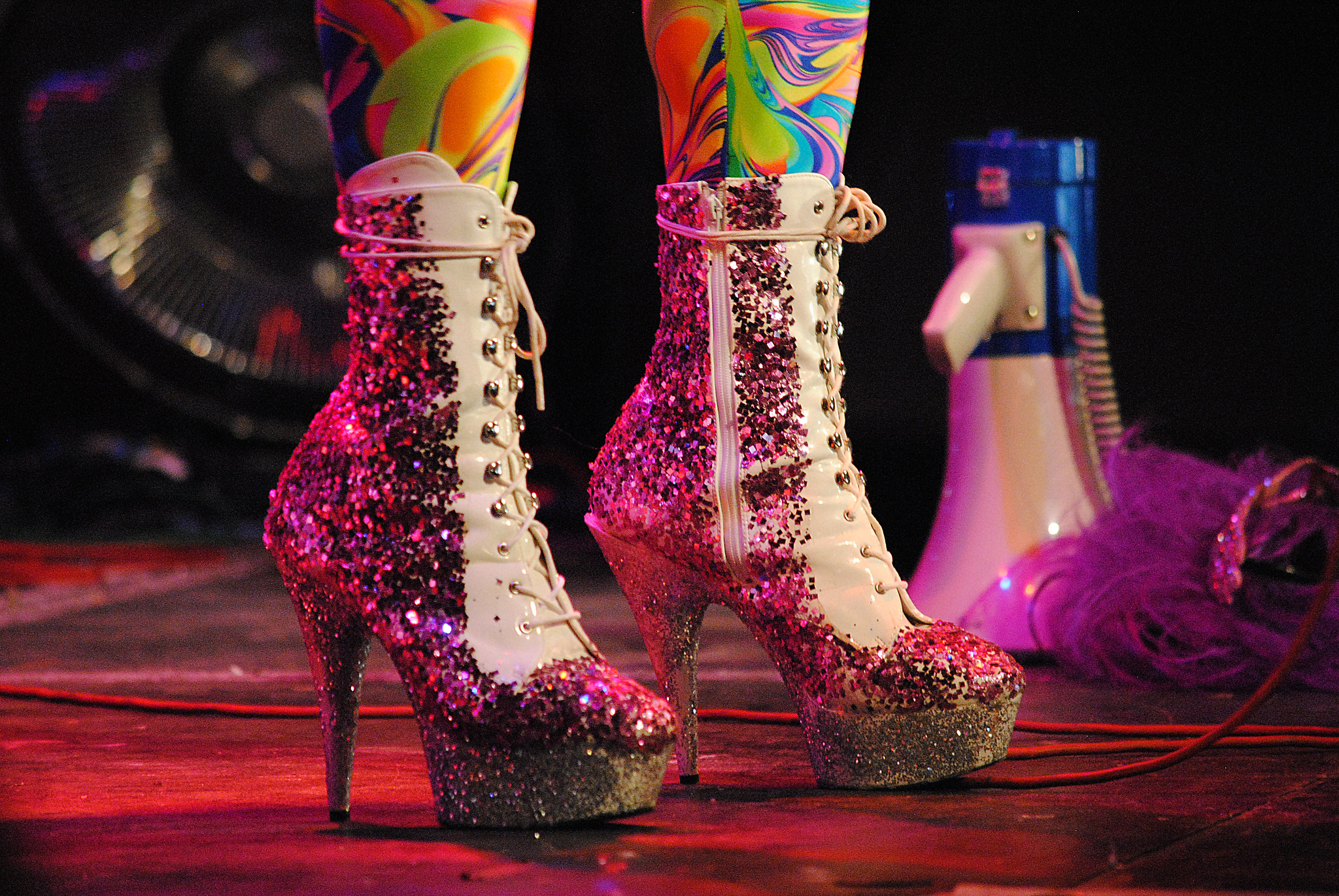 Person wear spiky stiletto platform shoes with glitter with a megaphone in the background