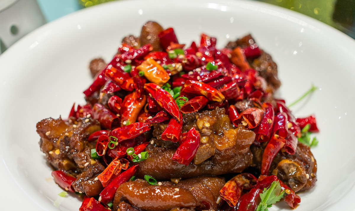 close up of a white bowl filled with marinated beef with spicy red chiles