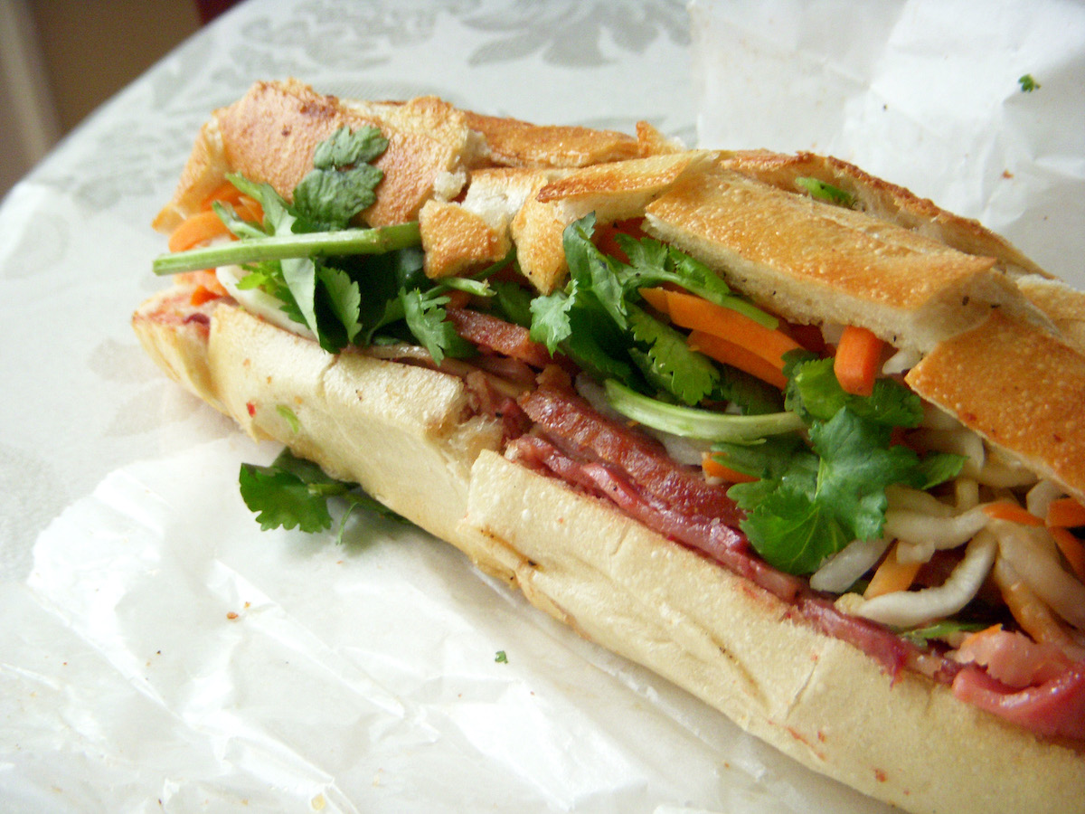 Banh mi sandwich on a baguette with pork, cilantro, and vegetables