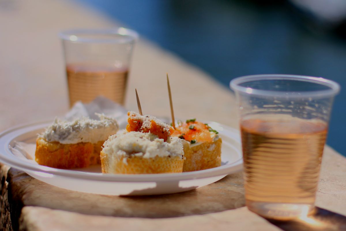 small bites of food and plastic cups of rose wine by a pool