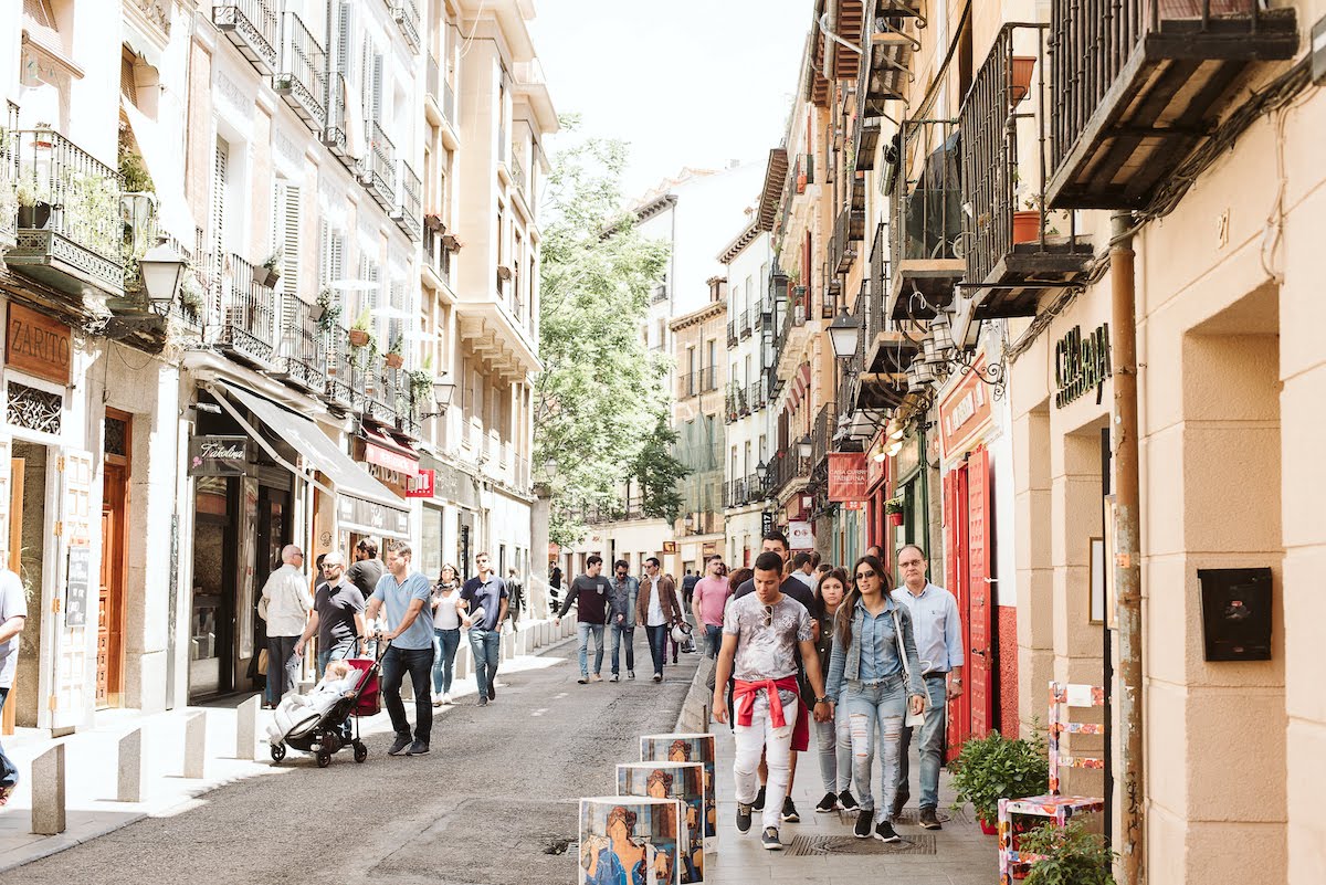 Street lined with bars in an urban neighborhood on a busy afternoon.