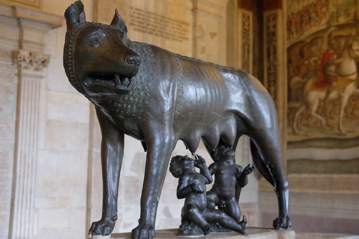 Bronze statue of two small figures nursing beneath a wolf