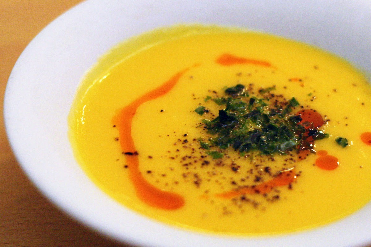 Yellow creamy vegetable soup garnished with herbs