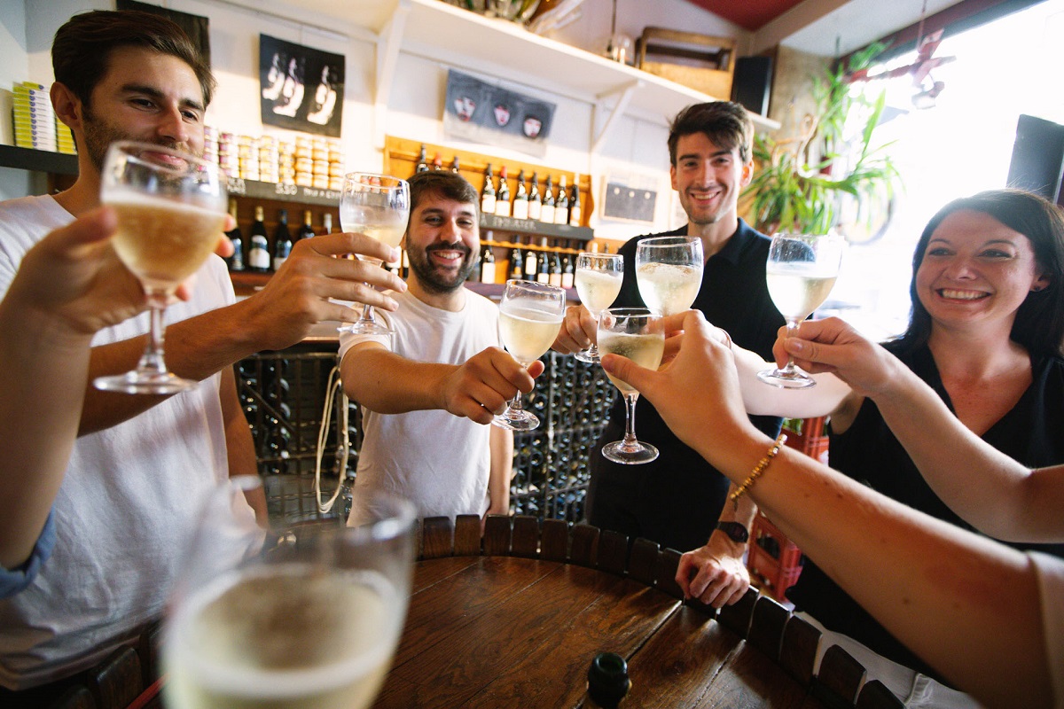 Group of friends toasting with white wine at a wine bar in Bordeaux