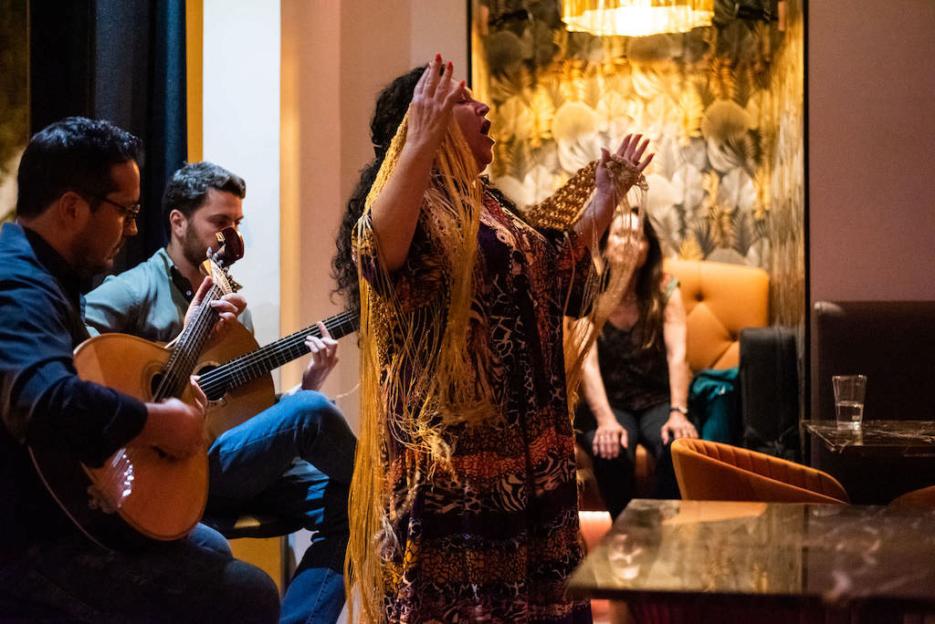 Fado show with singer, guitarists, and viewers at a restaurant in Lisbon, Portugal