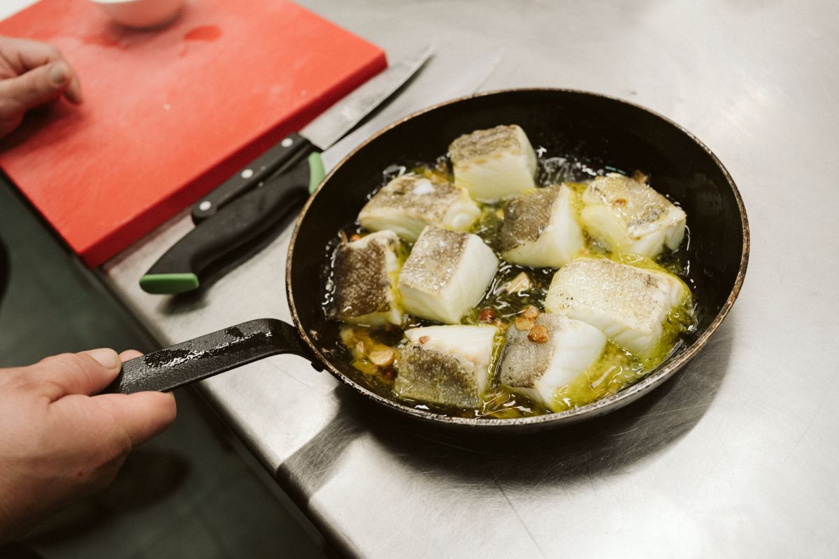 White fish being cooked in a pan