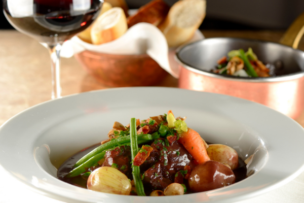 Dish of boeuf bourguignon with red wine on the side